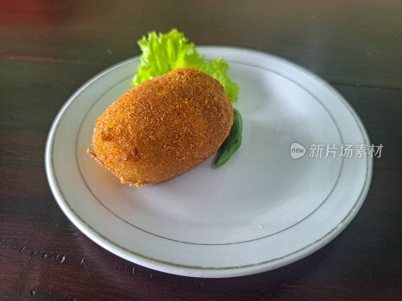 美味的炸土豆丸子或Kentang Kroket与生菜和辣椒在盘子里。小吃菜单。